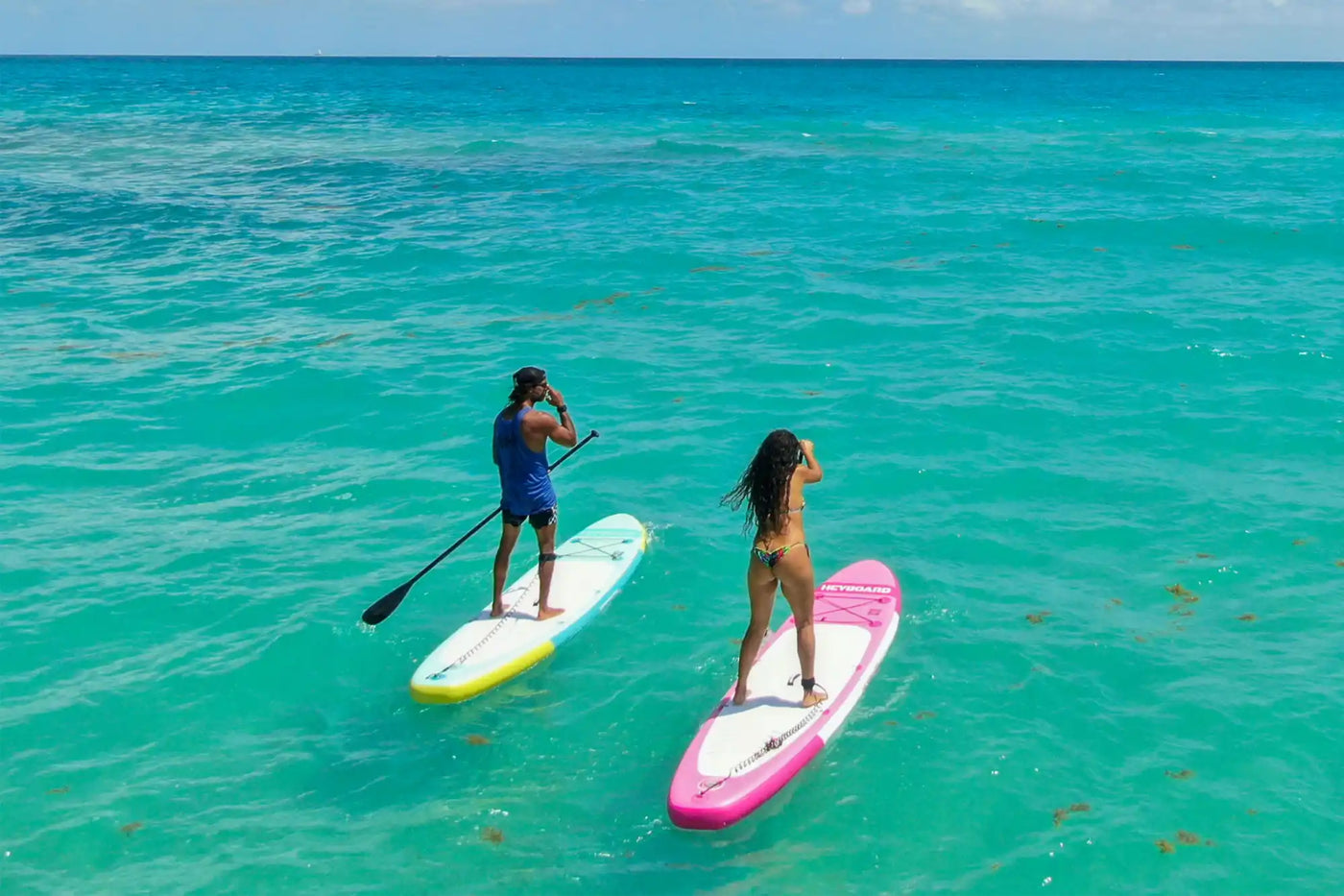 Two paddleboarders on turquoise water.