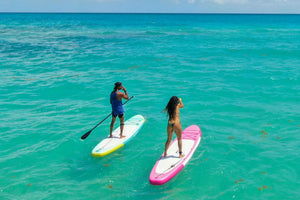 Two paddleboarders on turquoise water.